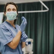 Enfermera en una mascarilla poniéndose guantes