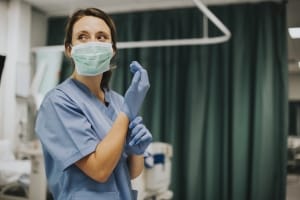 Enfermera en una mascarilla poniéndose guantes