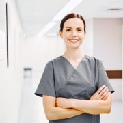 Woman in grey scrubs with arms folded