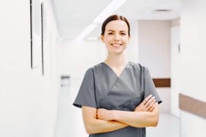 Woman in grey scrubs with arms folded