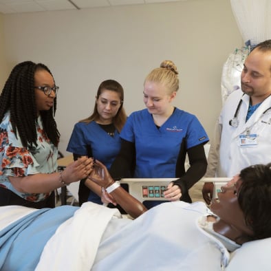 Four students practicing with a simulation mannequin