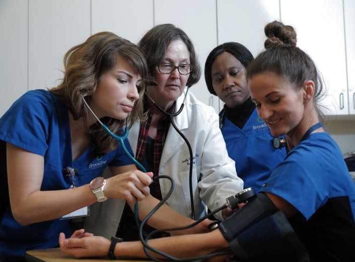 A group of nursing students with an instructor checking the blood pressure of another student