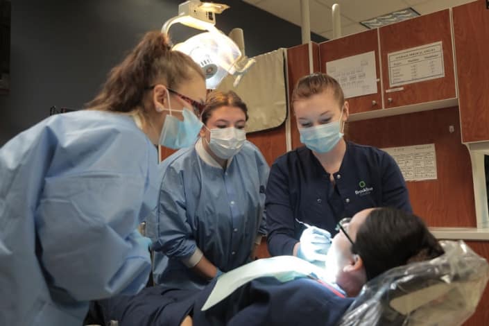 Dental assistant students getting hands-on practice on another student
