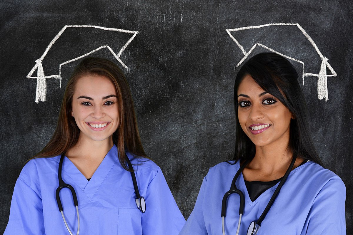 Two smiling graduates against a blackboard