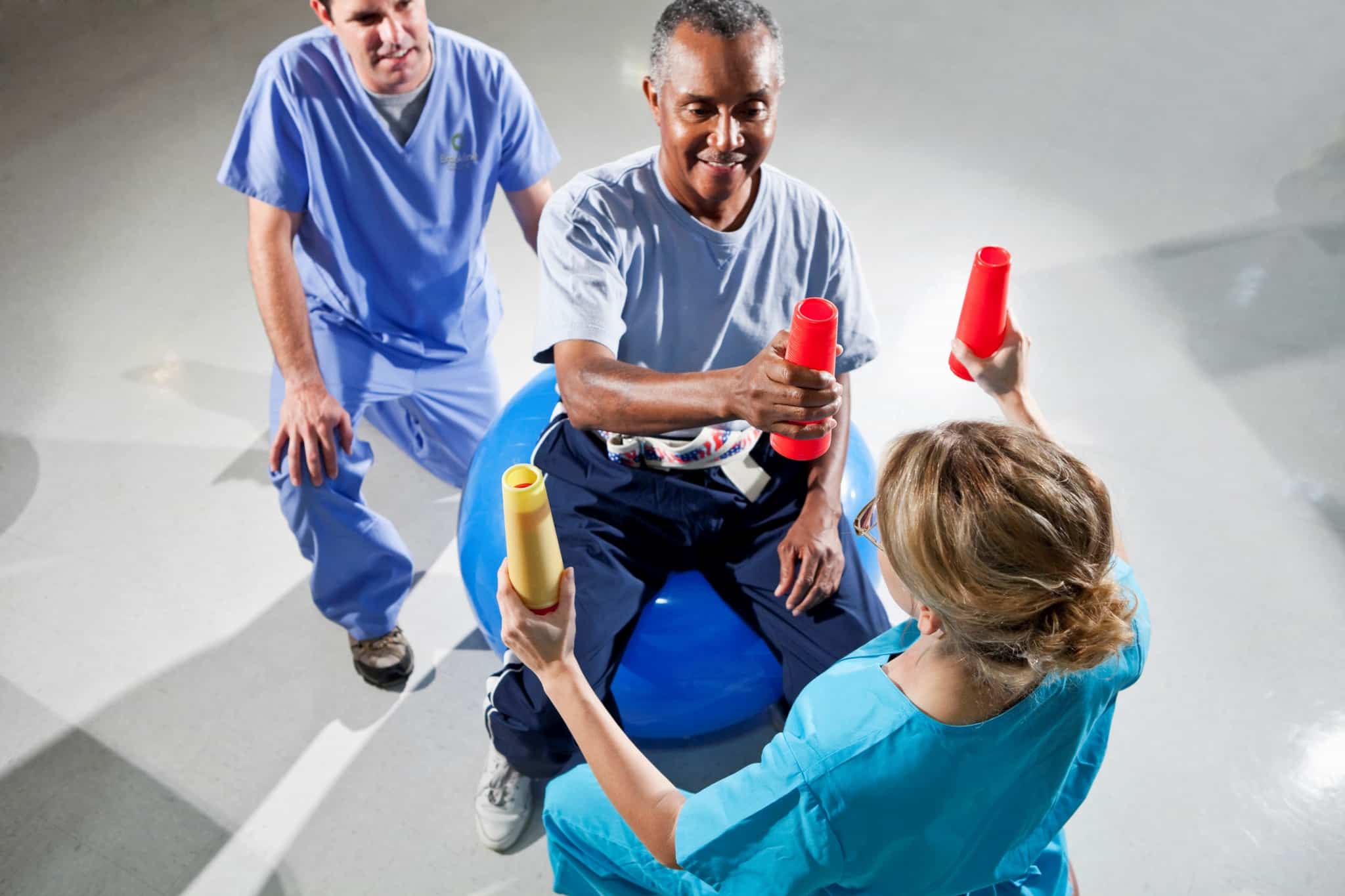Senior man with physical therapists using stability ball