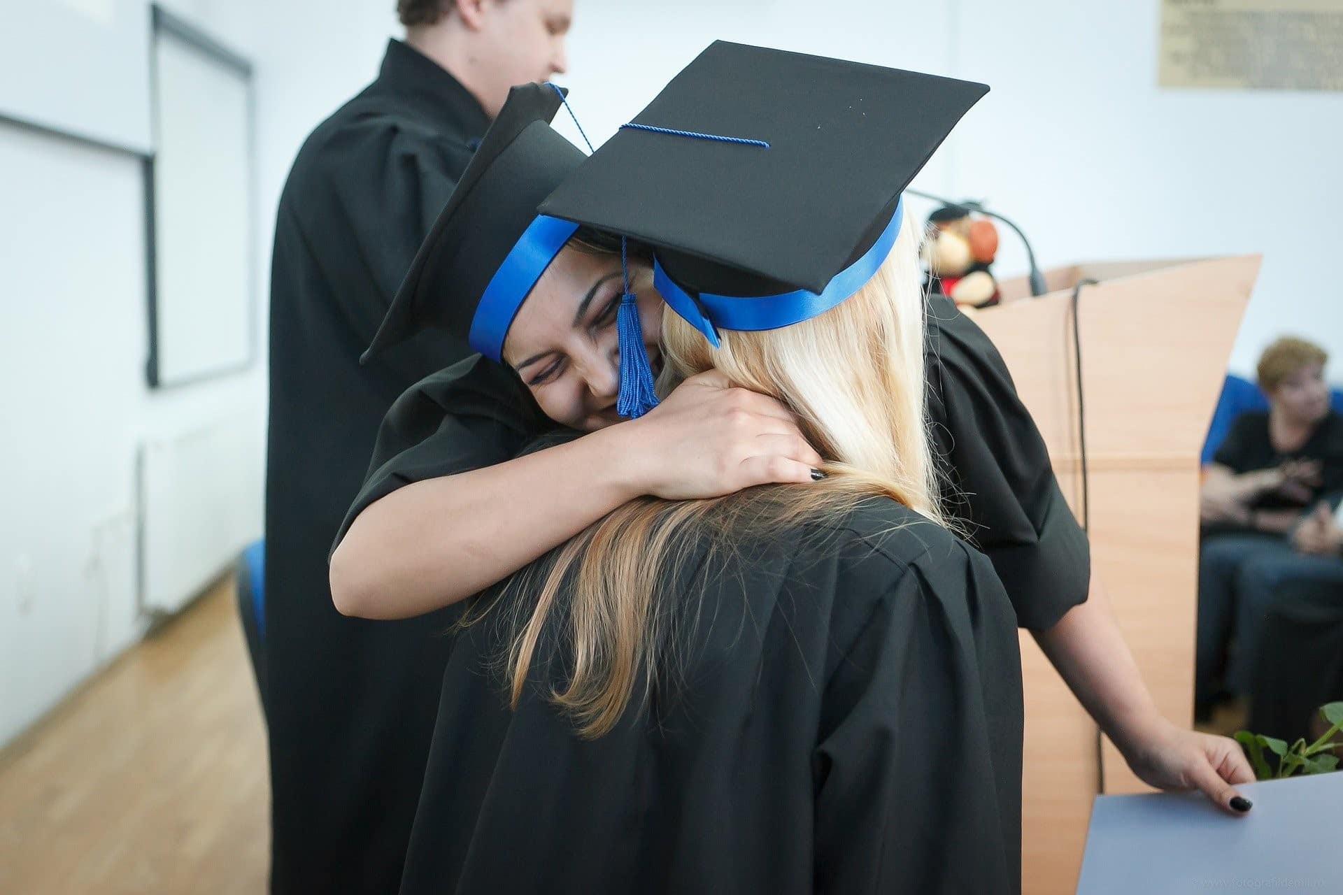 Smiling graduates hugging on stage