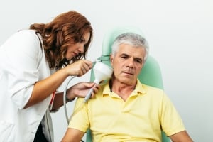 Profesional sanitario irrigando el oído de un paciente