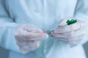 Gloved hands holding a catheter