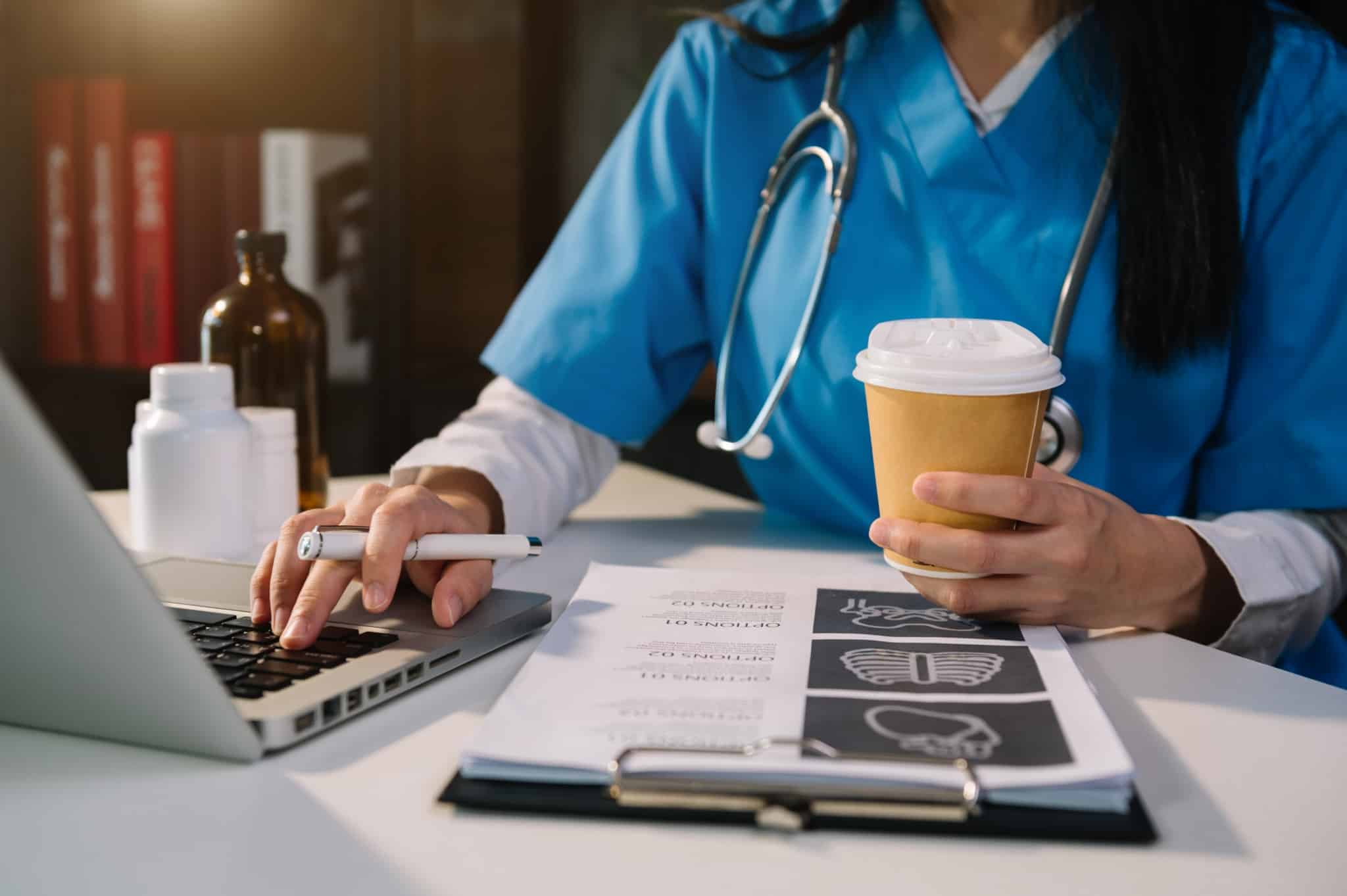 Healthcare professional typing on a laptop