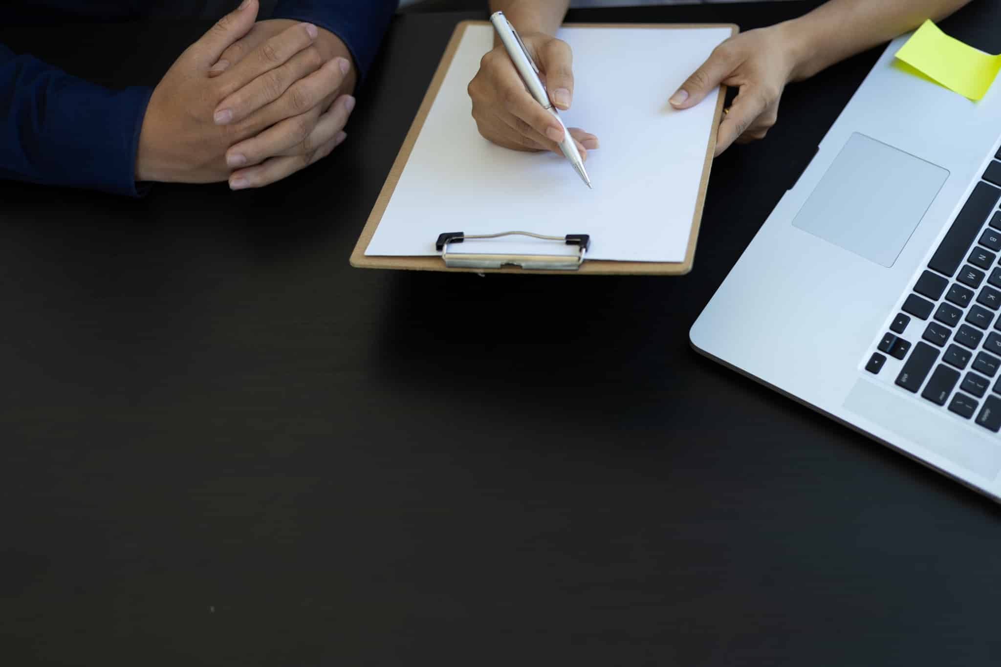 Close up of a clipboard and a laptop