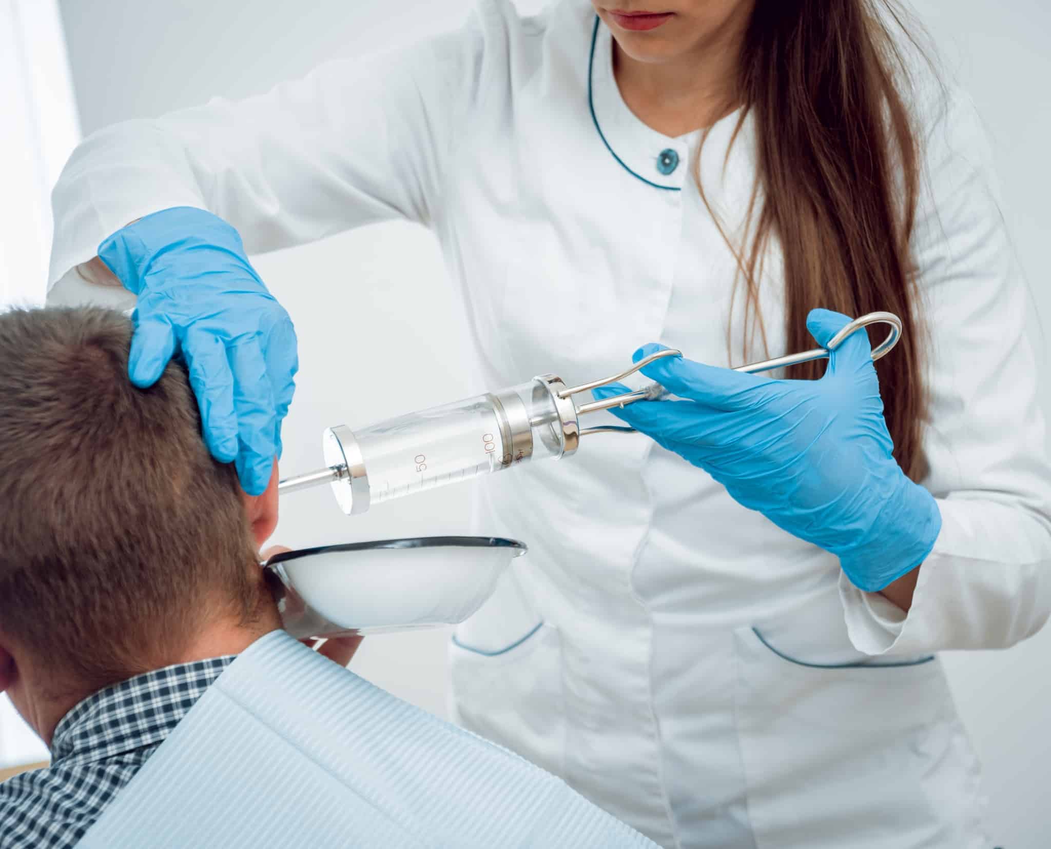 Medical professional irrigating a patient's ear