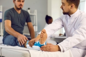 Profesional médico que examina el tobillo de un paciente