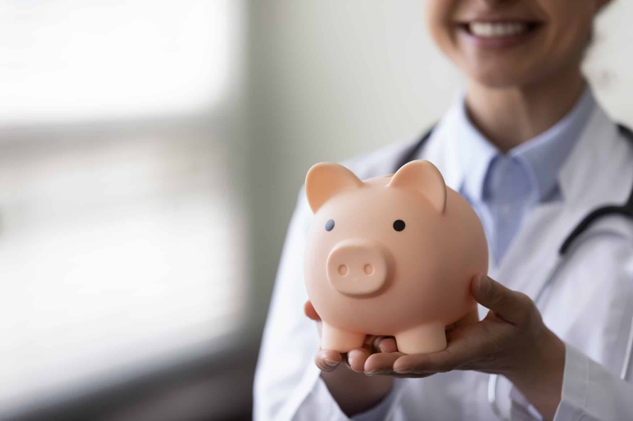 Medical professional holding a piggy bank