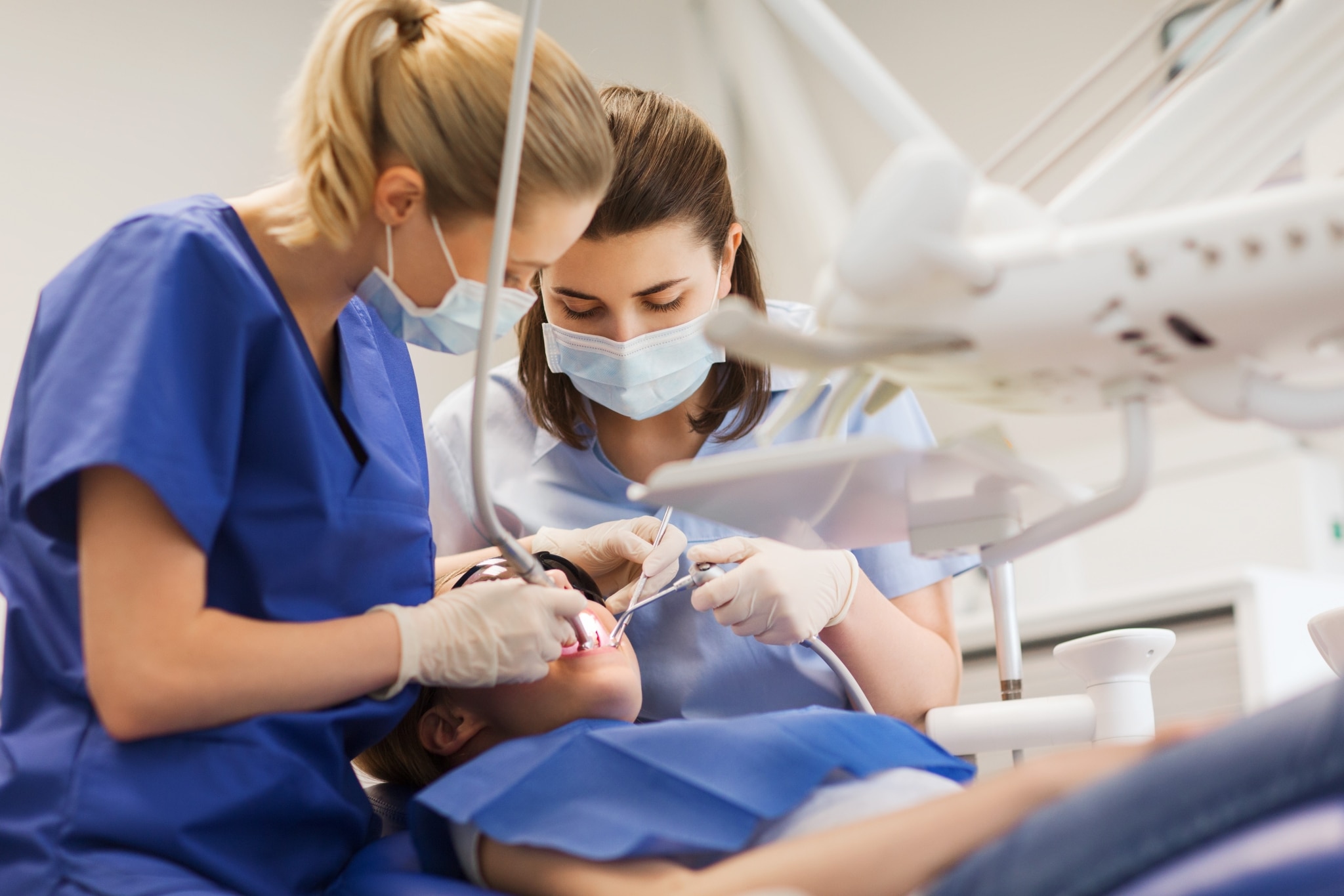 Female dental workers examining a young patient