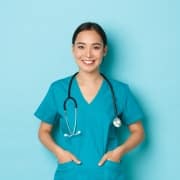 Asian nurse standing against a blue backdrop