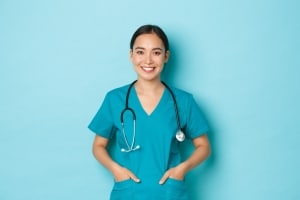 Asian nurse standing against a blue backdrop
