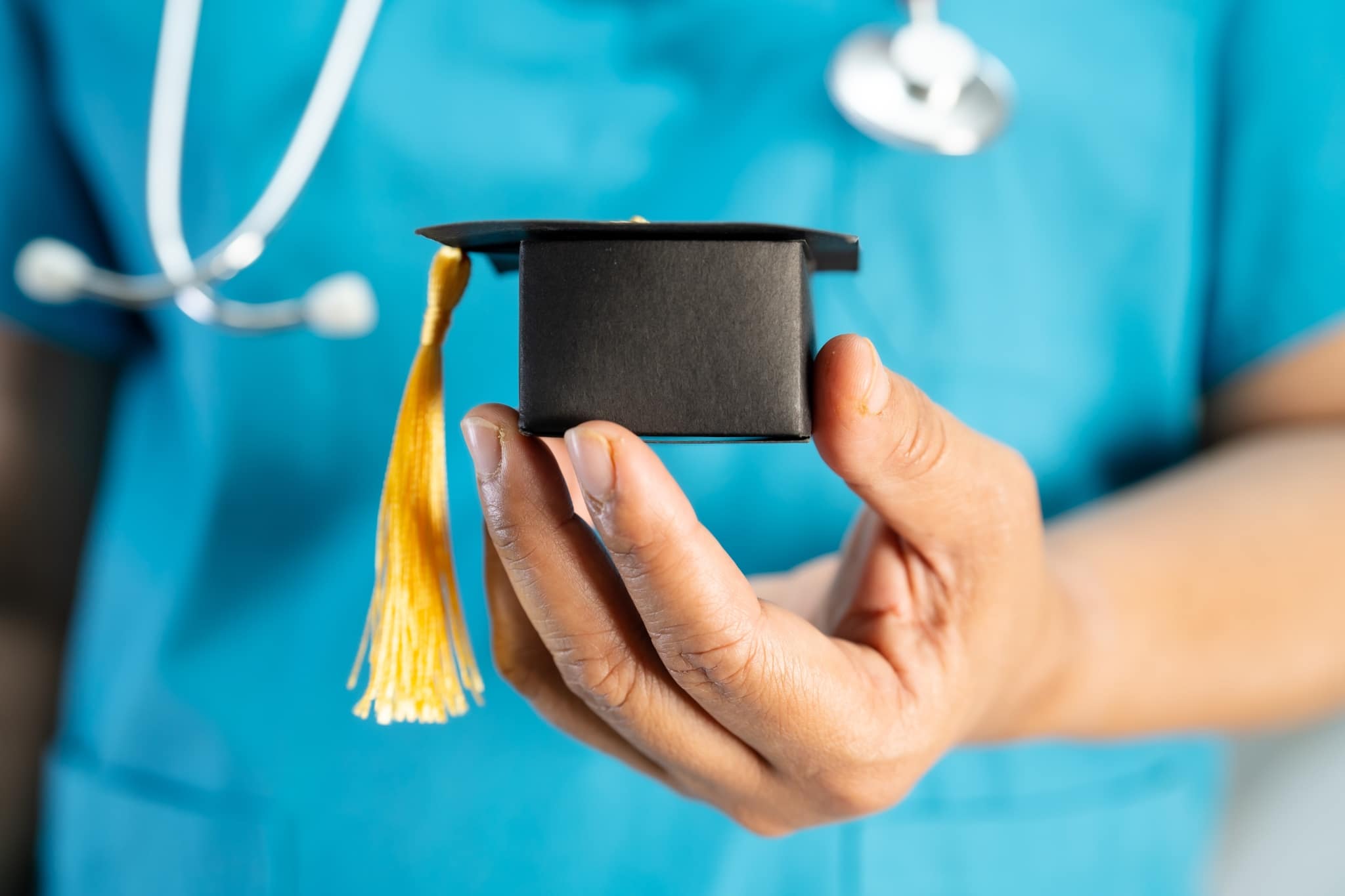 Close up of a nurse holding a replica graduation cap