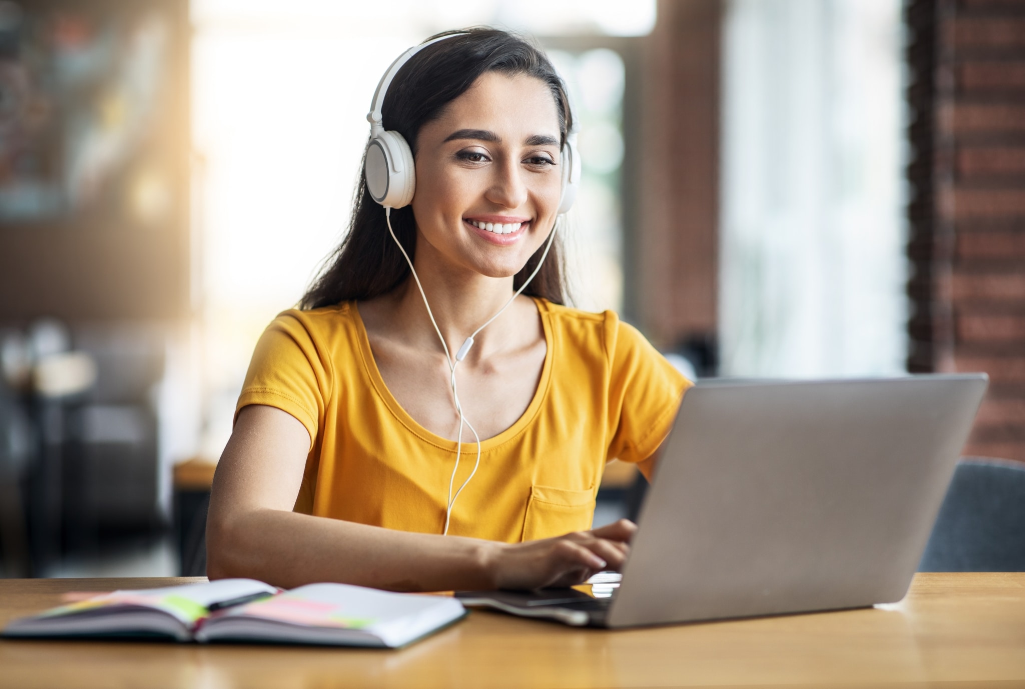 Smiling young woman wearing headphones on a laptop