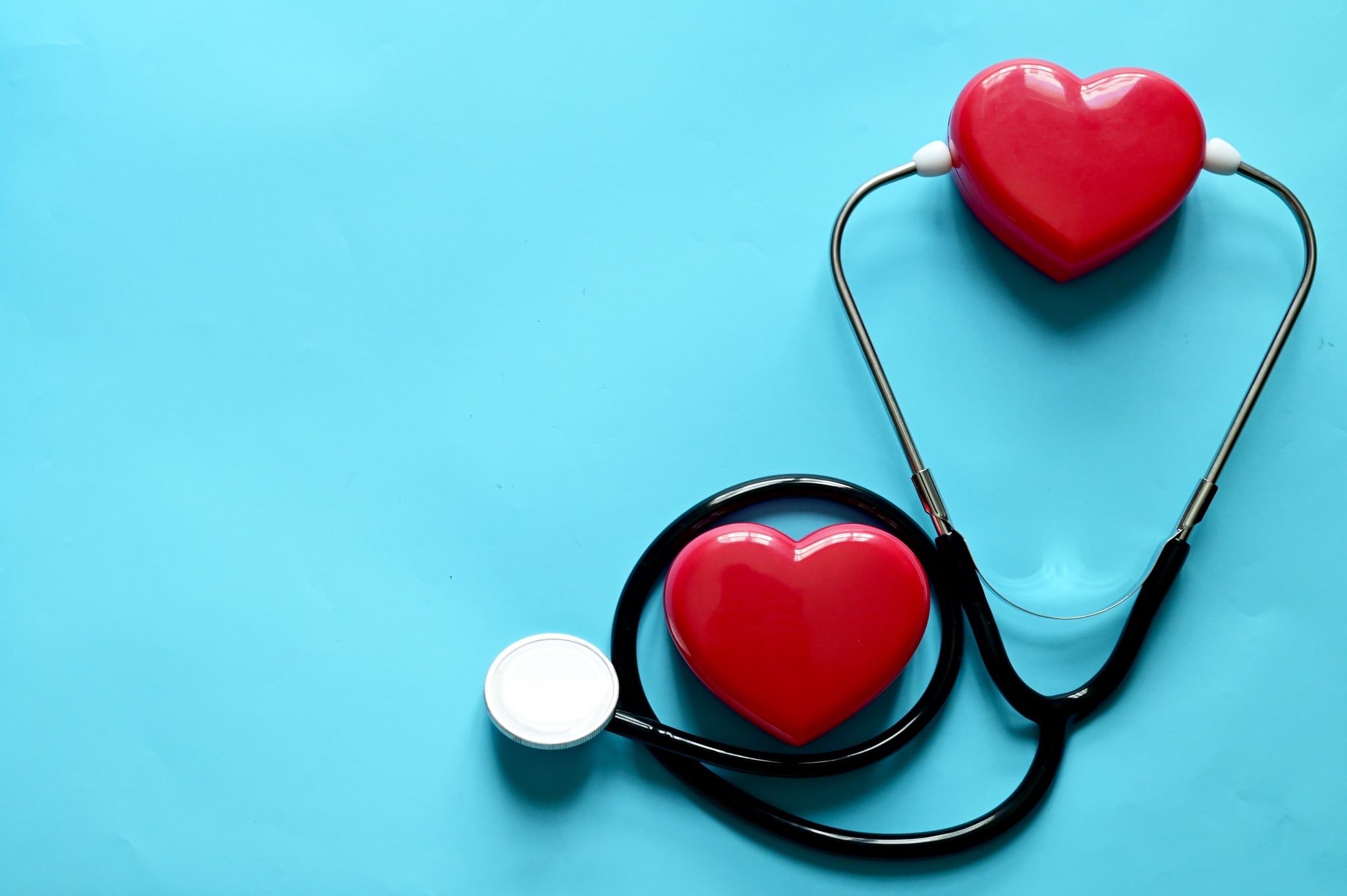 Stethoscope and plastic hearts against a blue background
