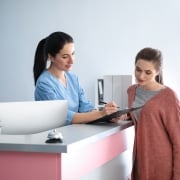 Young medical receptionist with a female patient