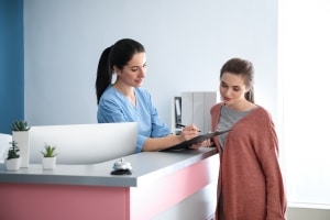 Young medical receptionist with a female patient
