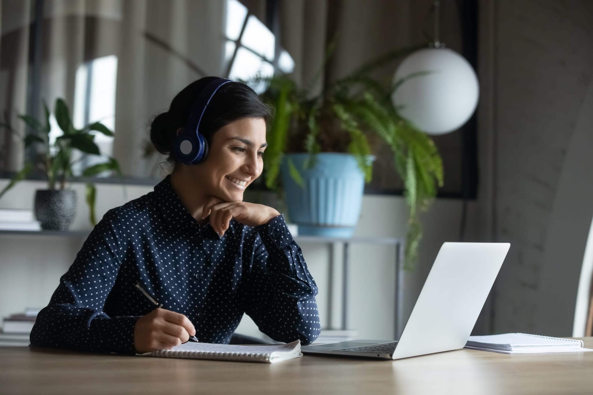 Young Indian woman using wireless headphones and a laptop