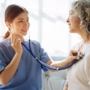 Nurse using a stethoscope on an elderly patient