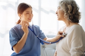 Nurse using a stethoscope on an elderly patient
