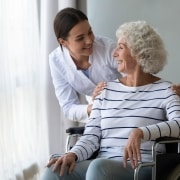 Profesional médico sonriente con un paciente anciano en silla de ruedas