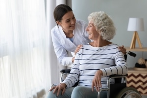 Profesional médico sonriente con un paciente anciano en silla de ruedas