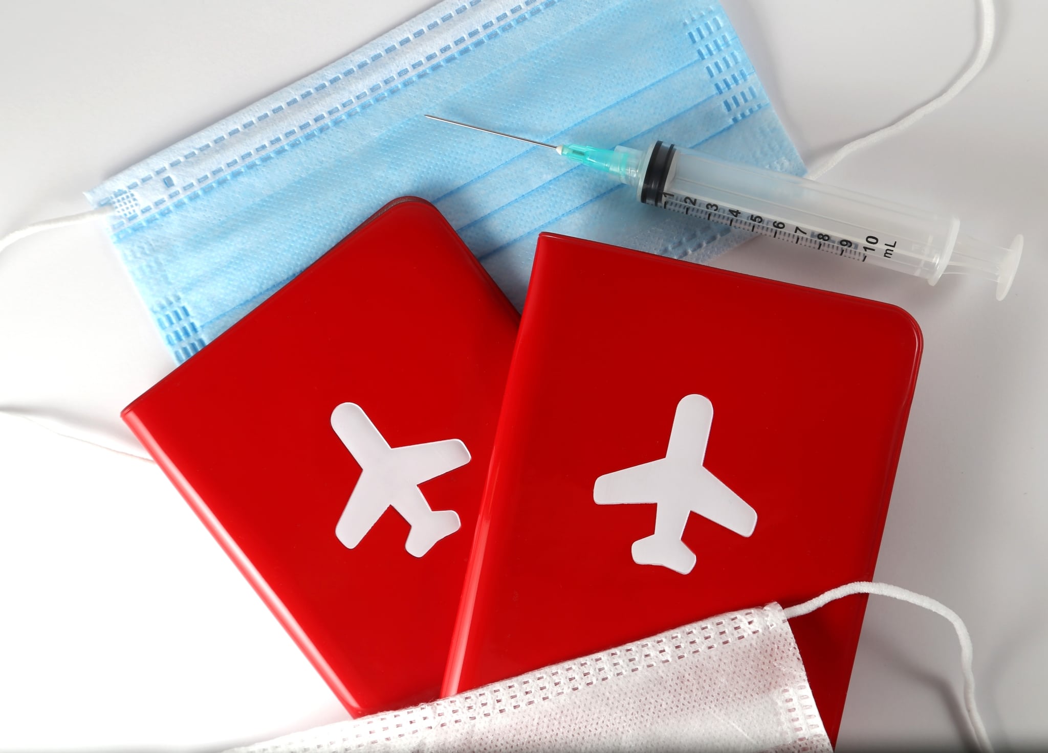 Close up of a medical mask, passports, and a syringe