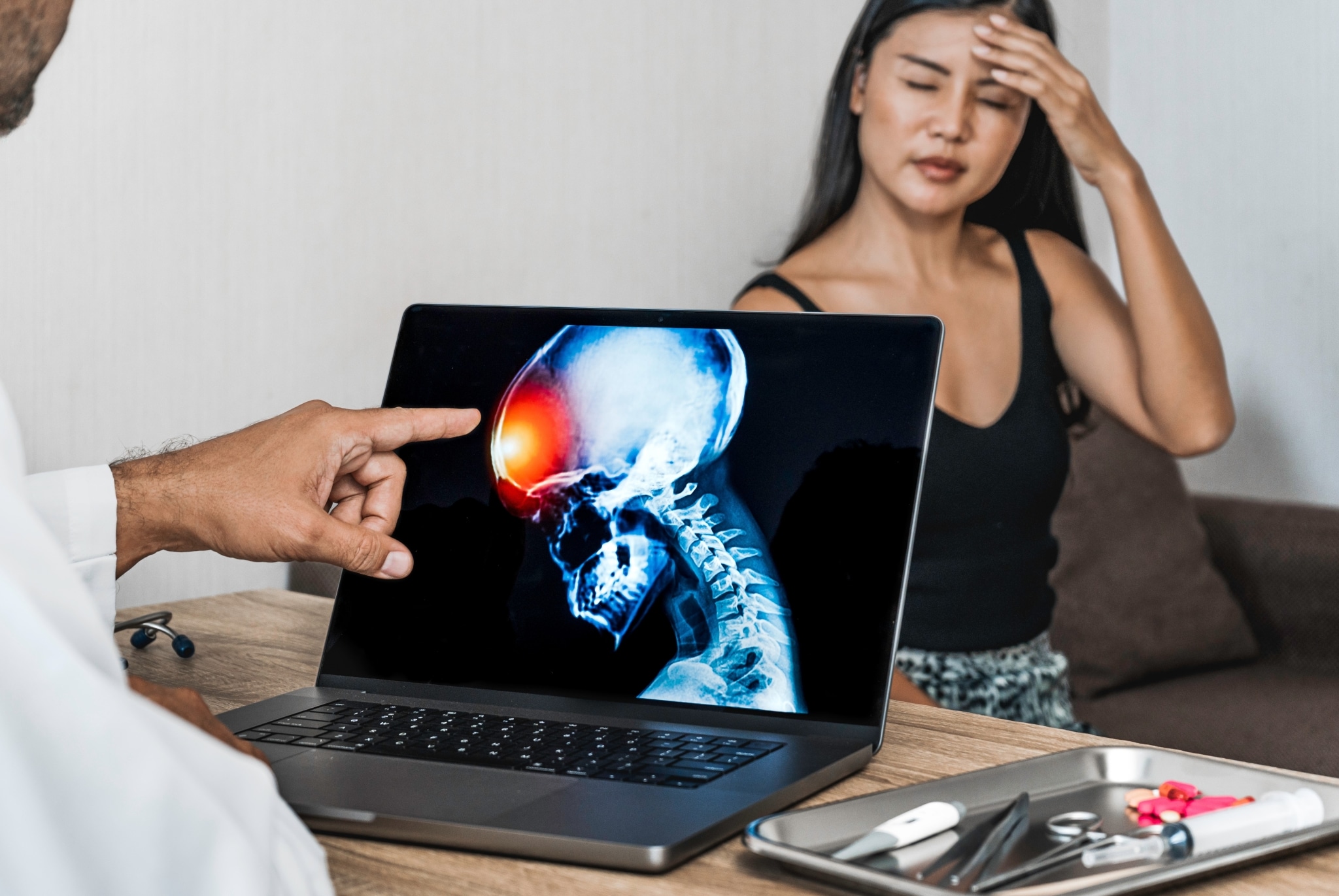 Asian woman holding her head while doctor examines test results