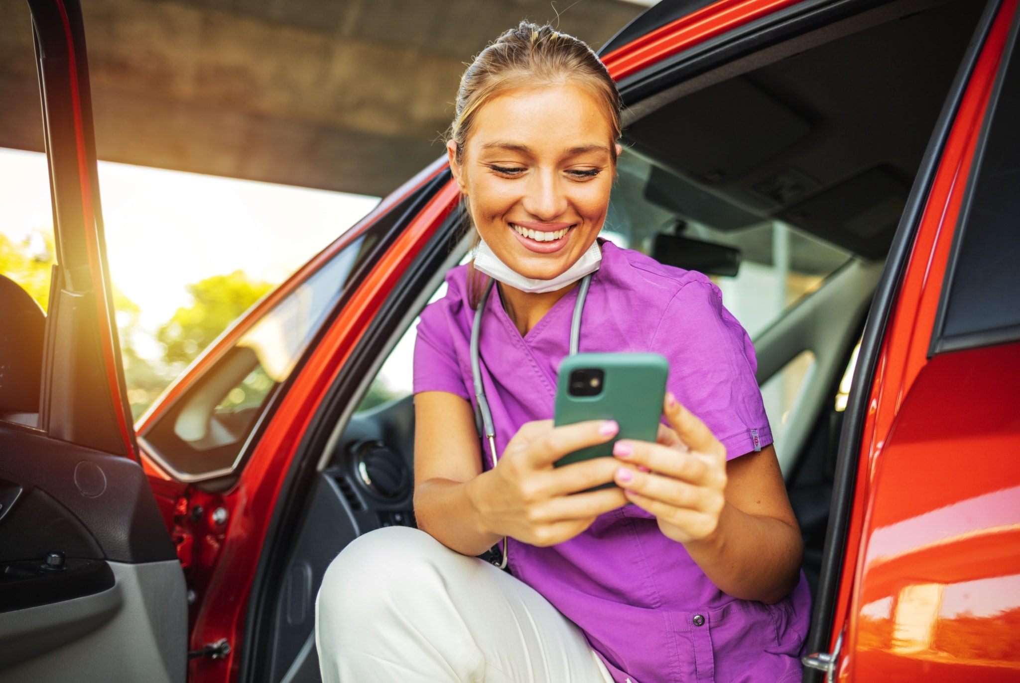 Smiling nurse in scrubs looking at her phone