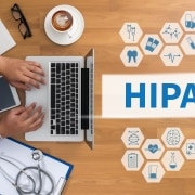 Vista aérea de un hombre en una computadora portátil y símbolos virtuales junto a un cartel que dice HIPAA