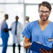 Enfermero sonriente con gafas sosteniendo el historial de un paciente