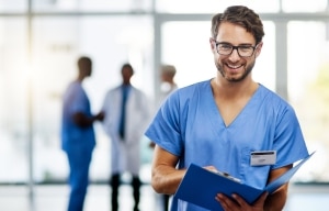 Enfermero sonriente con gafas sosteniendo el historial de un paciente