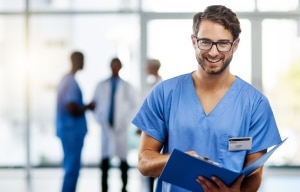 Smiling male nurse with glasses holding a patient's chart