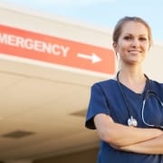 Young nurse standing in front of a sign that says EMERGENCY