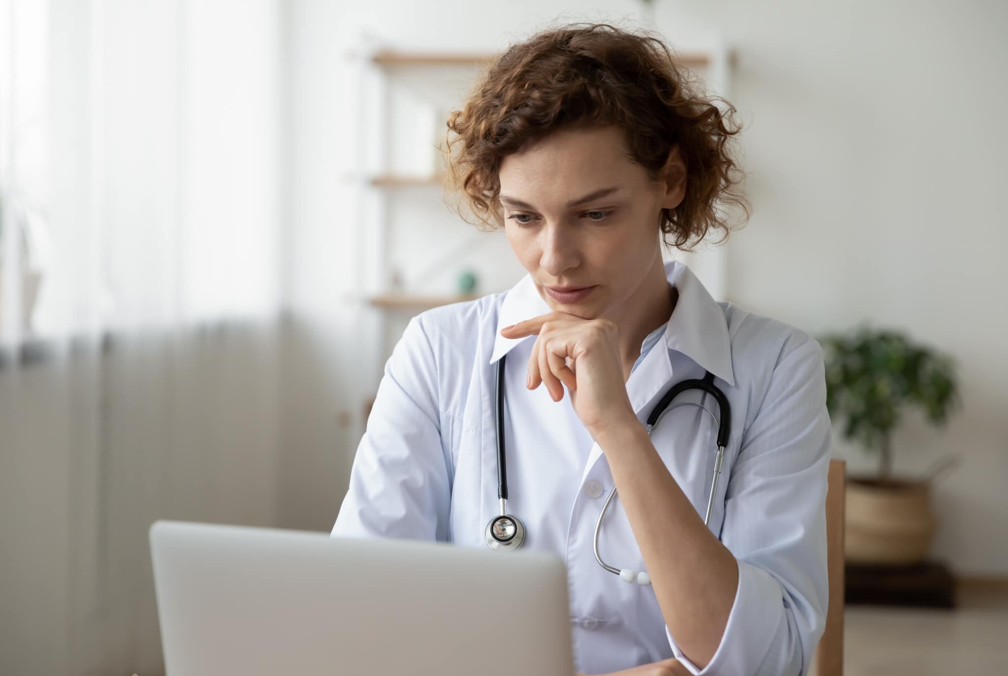 Female nurse deep in thought while using a laptop