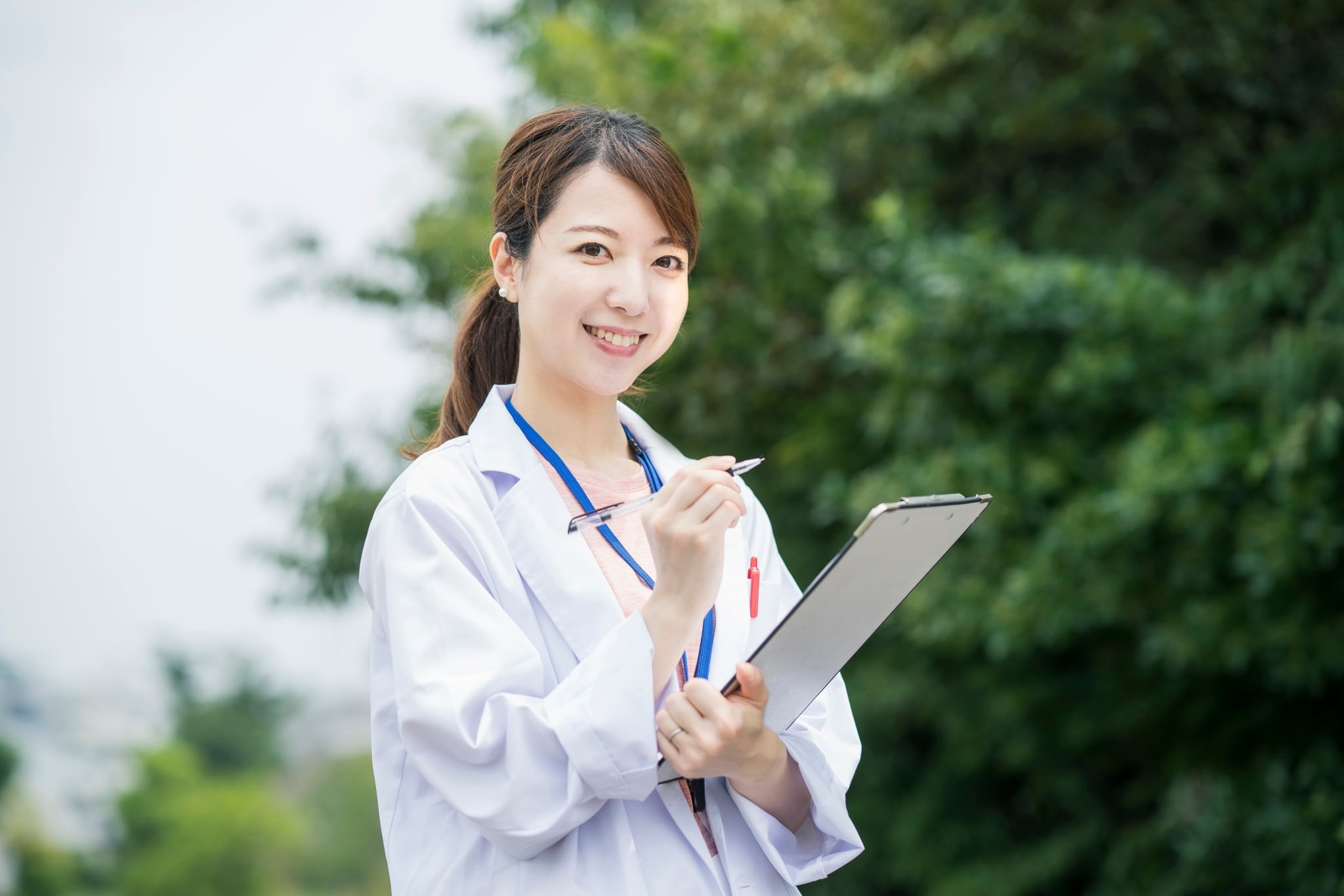 Asian medical professional writing on a clipboard outside