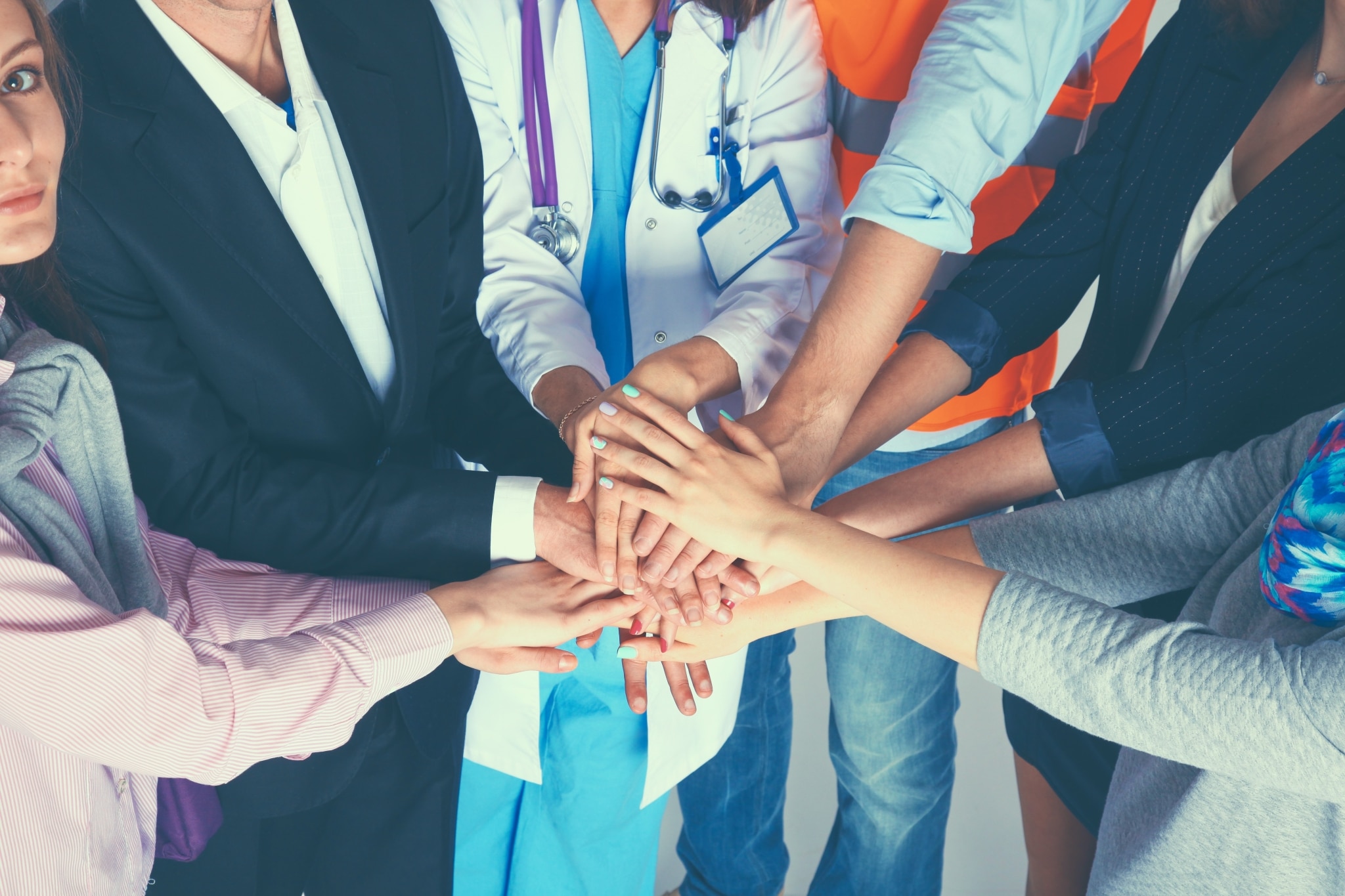 Various people touching hands in a teamwork gesture