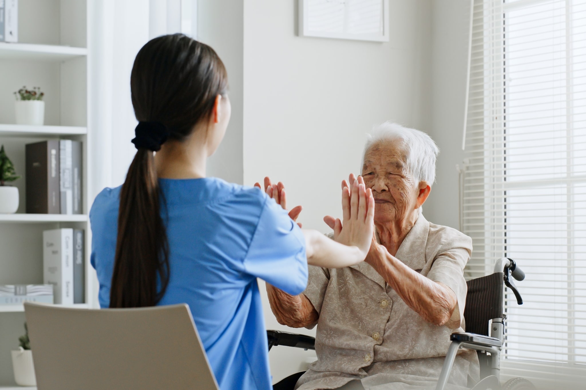 Enfermera asiática ayudando a un paciente anciano a hacer ejercicio