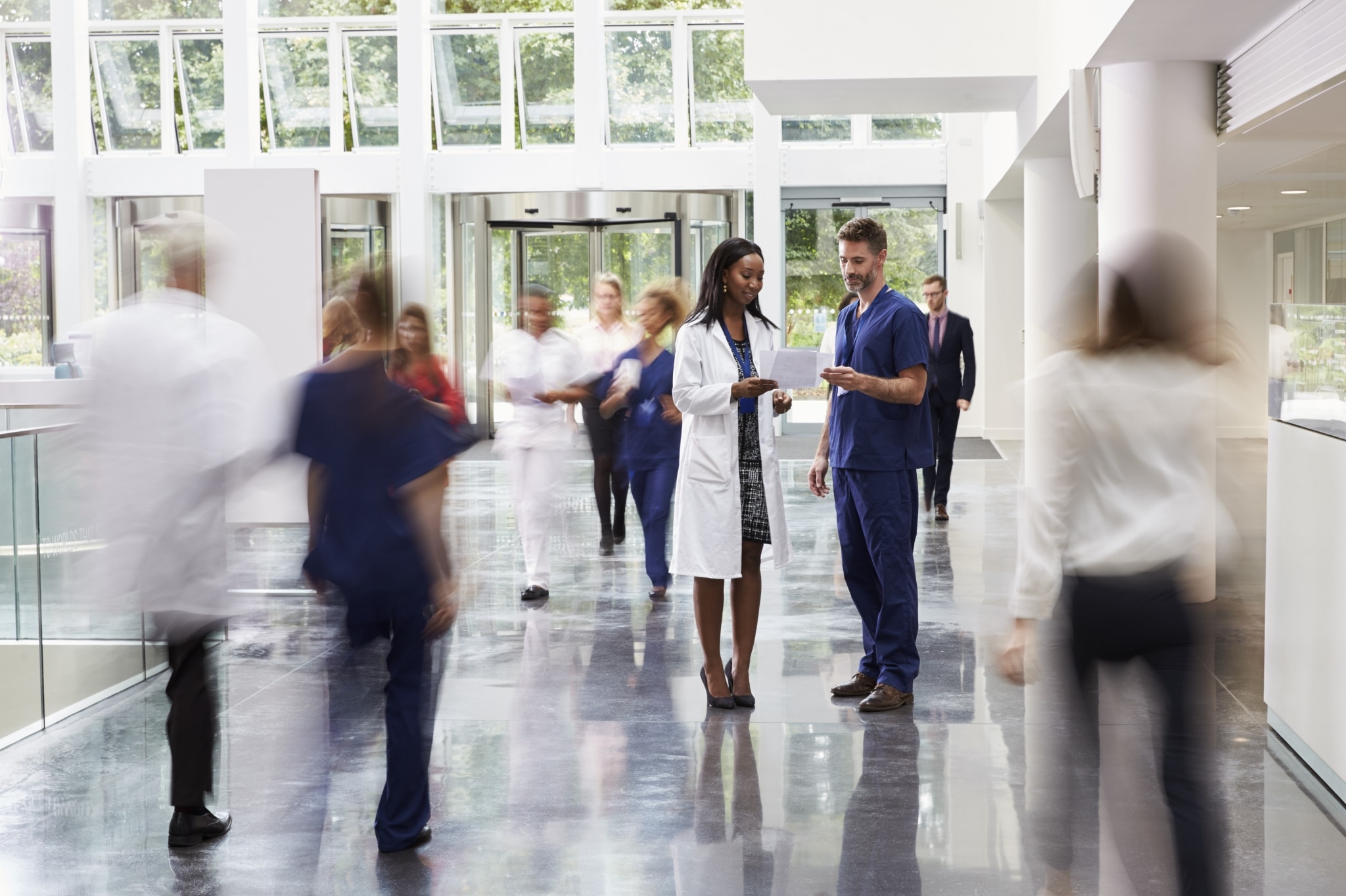 A nurse and a doctor speaking in a hospital hallway