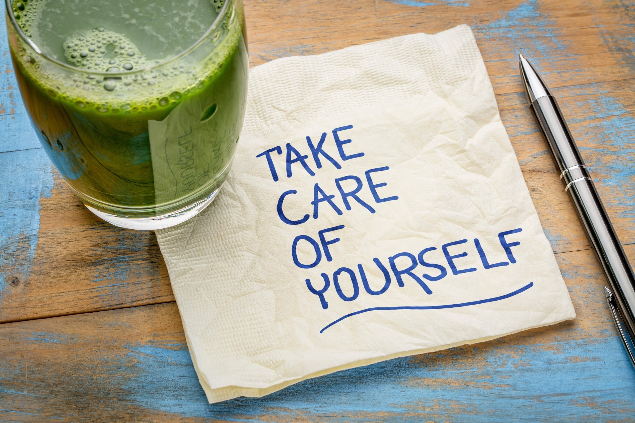 Close up of green juice and a napkin that says take care of yourself