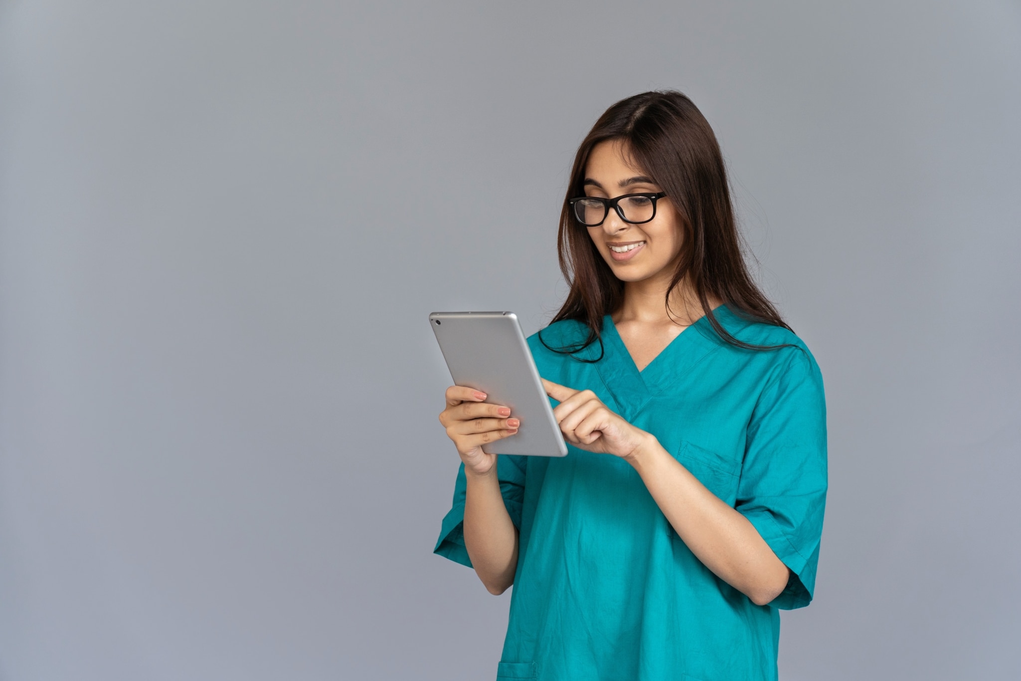 Smiling nurse wearing glasses and using a tablet