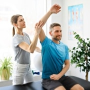Profesional de fisioterapia ayudando a un hombre a estirar el brazo y el hombro