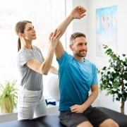 Physical therapy professional helping a man stretch his arm and shoulder