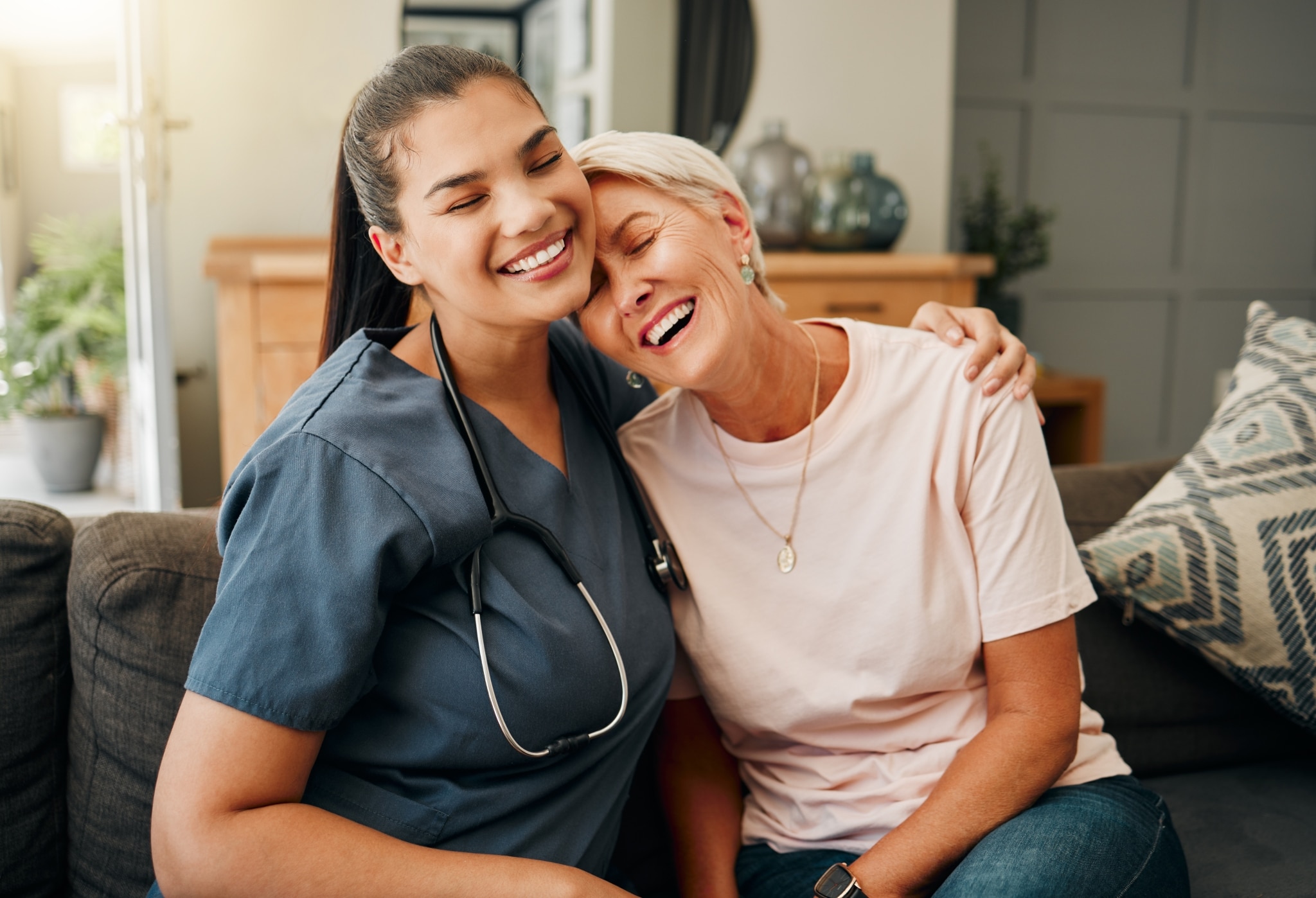 Nurse hugging an elderly woman on a couch