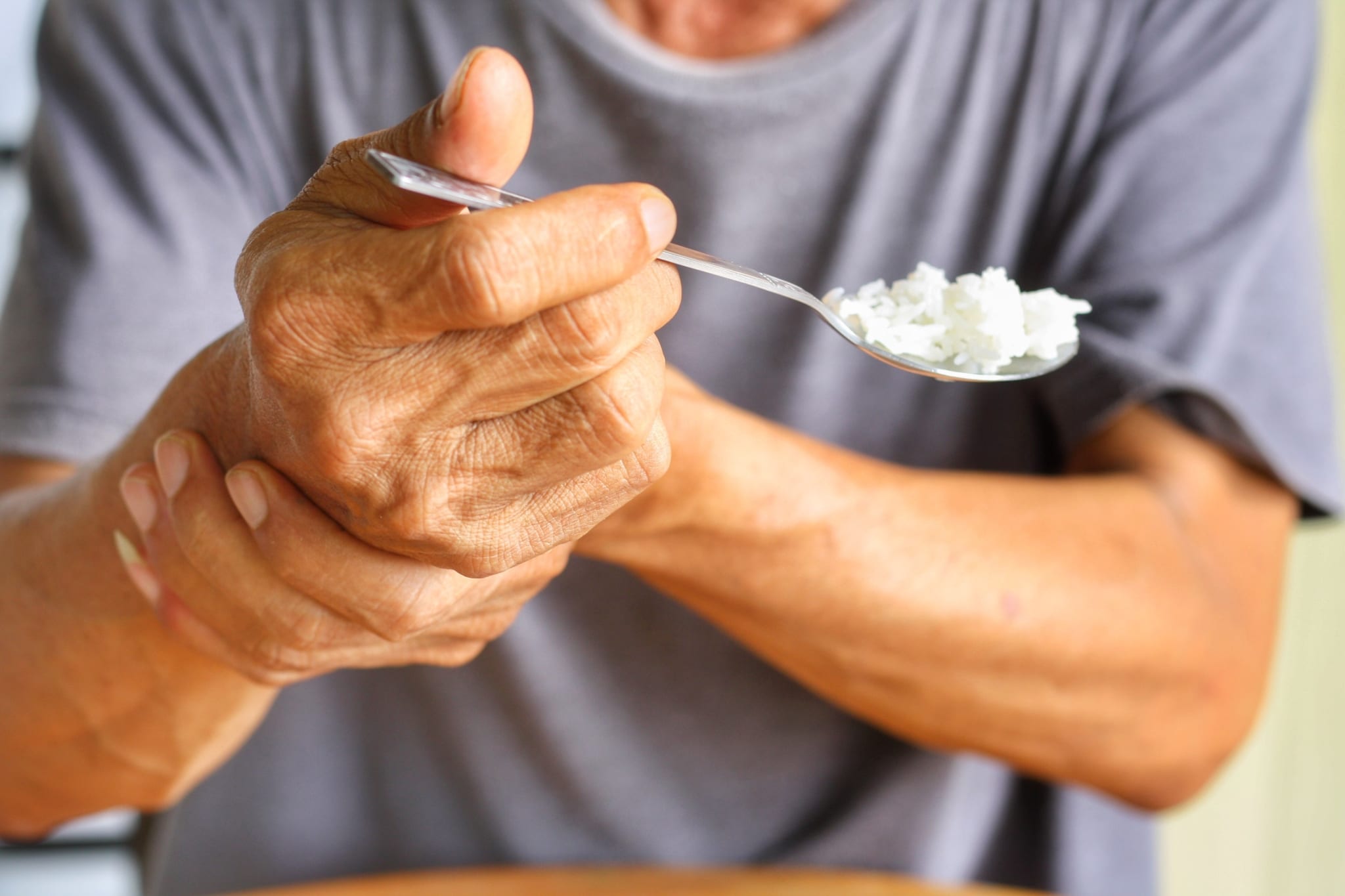 Close up of a man holding his wrist to stop tremors