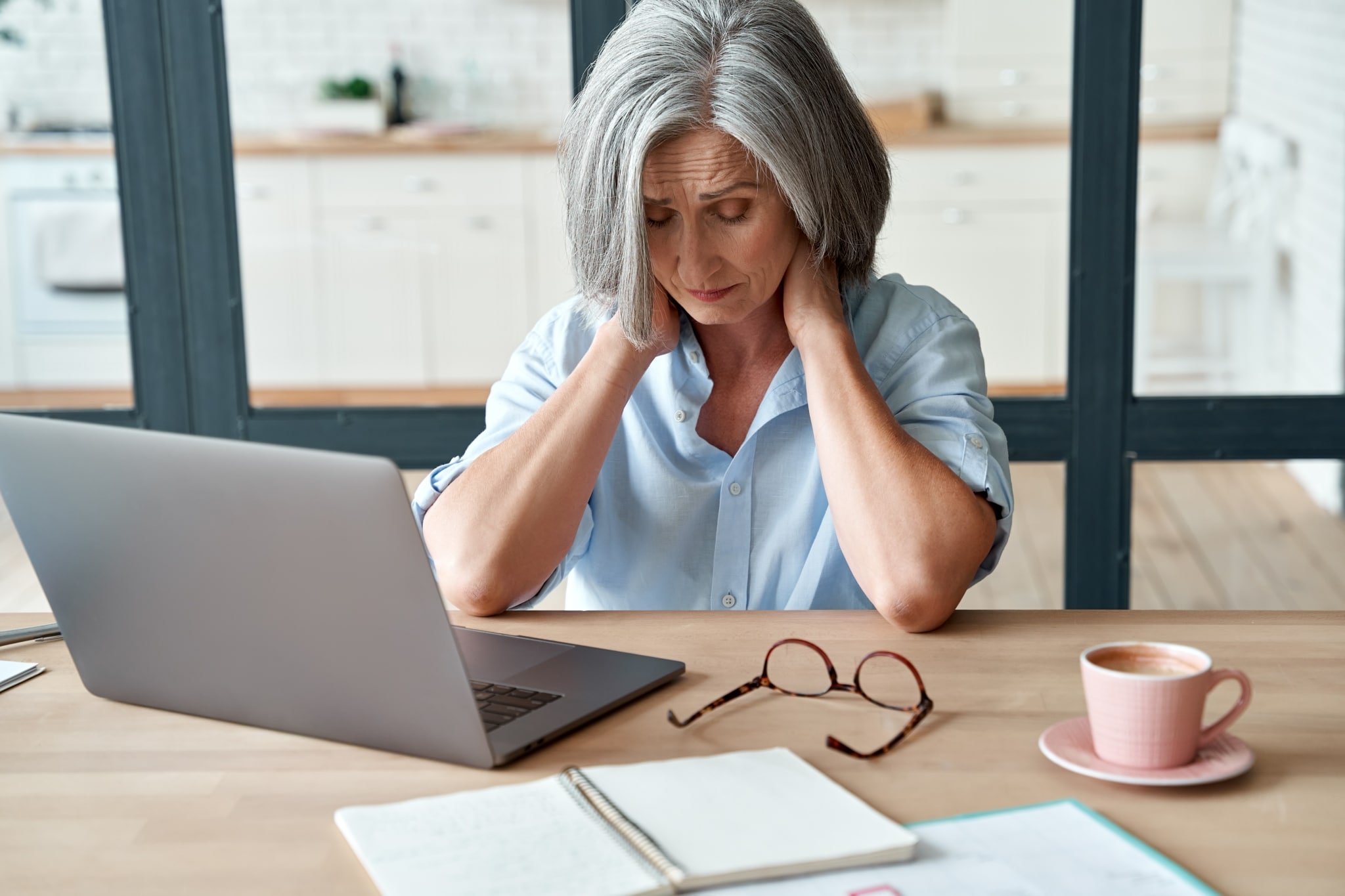 Older woman rubbing her neck at a desk